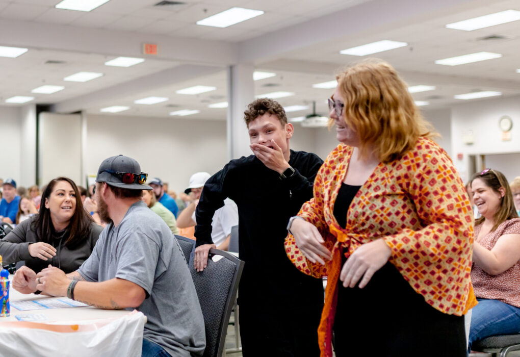 Young man and young woman laughing together in crowded room