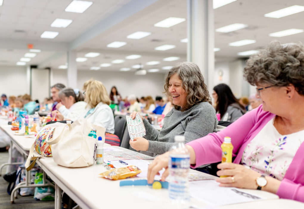 Smiling woman in grey shirt showing her bingo card